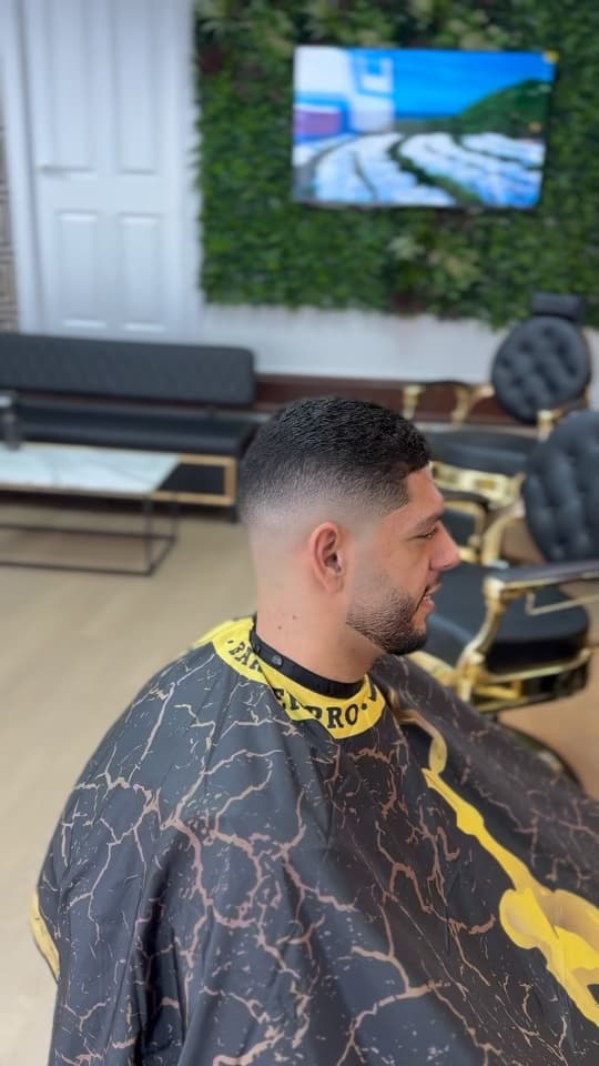 High skin fade with a short textured top and a trimmed beard, side profile